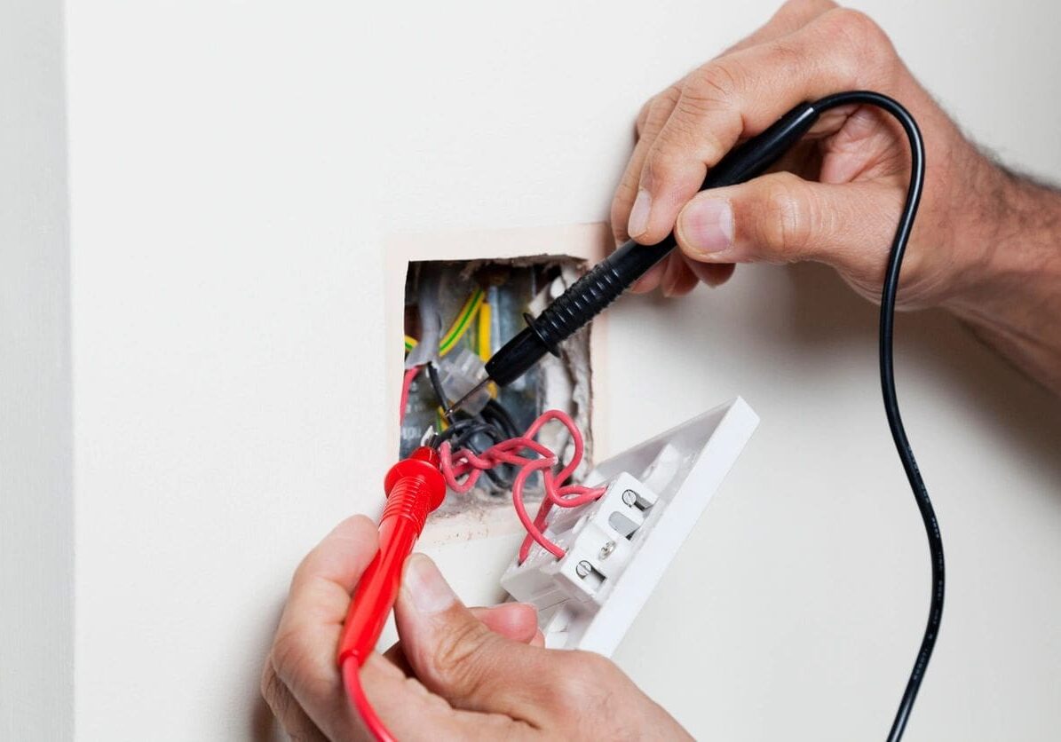 A person is cutting the wires of an electrical box.